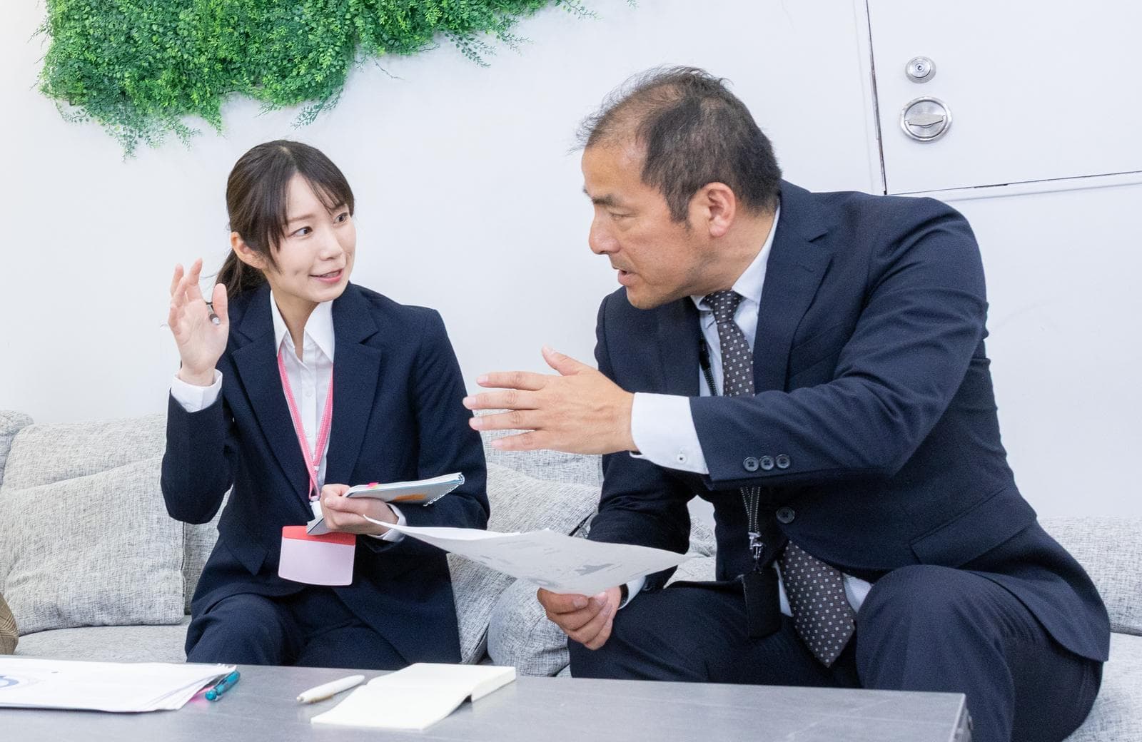 資料を説明する女性社員と話を聞かない上司の打ち合わせ風景
