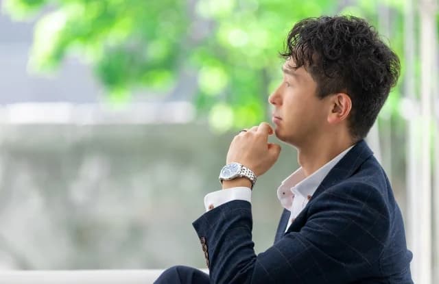 窓辺で考え込むスーツ姿の男性
