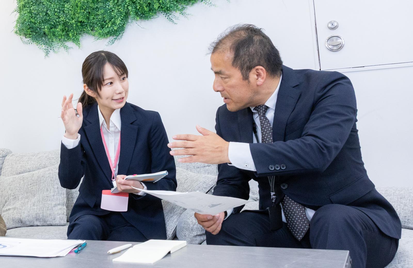 資料を説明する女性社員と話を聞かない上司の打ち合わせ風景