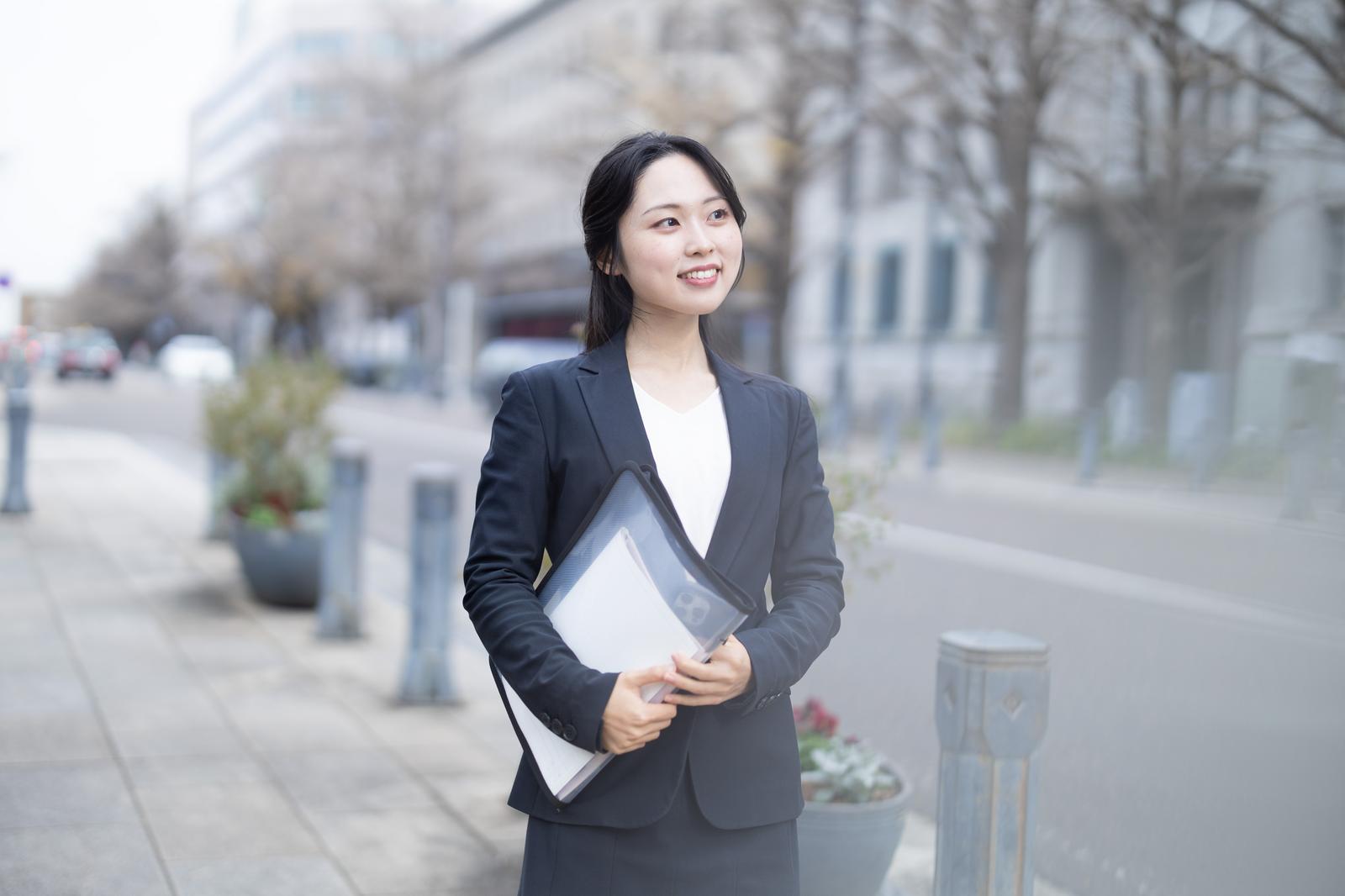 書類を持ってキャリアアップに向かうスーツ姿の女性