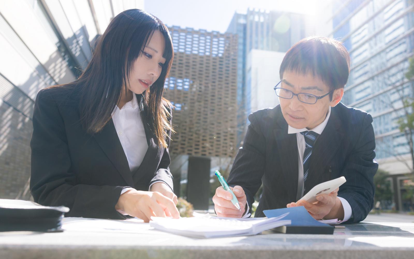 営業資料を見ながら職場の人間関係について考える上司と部下