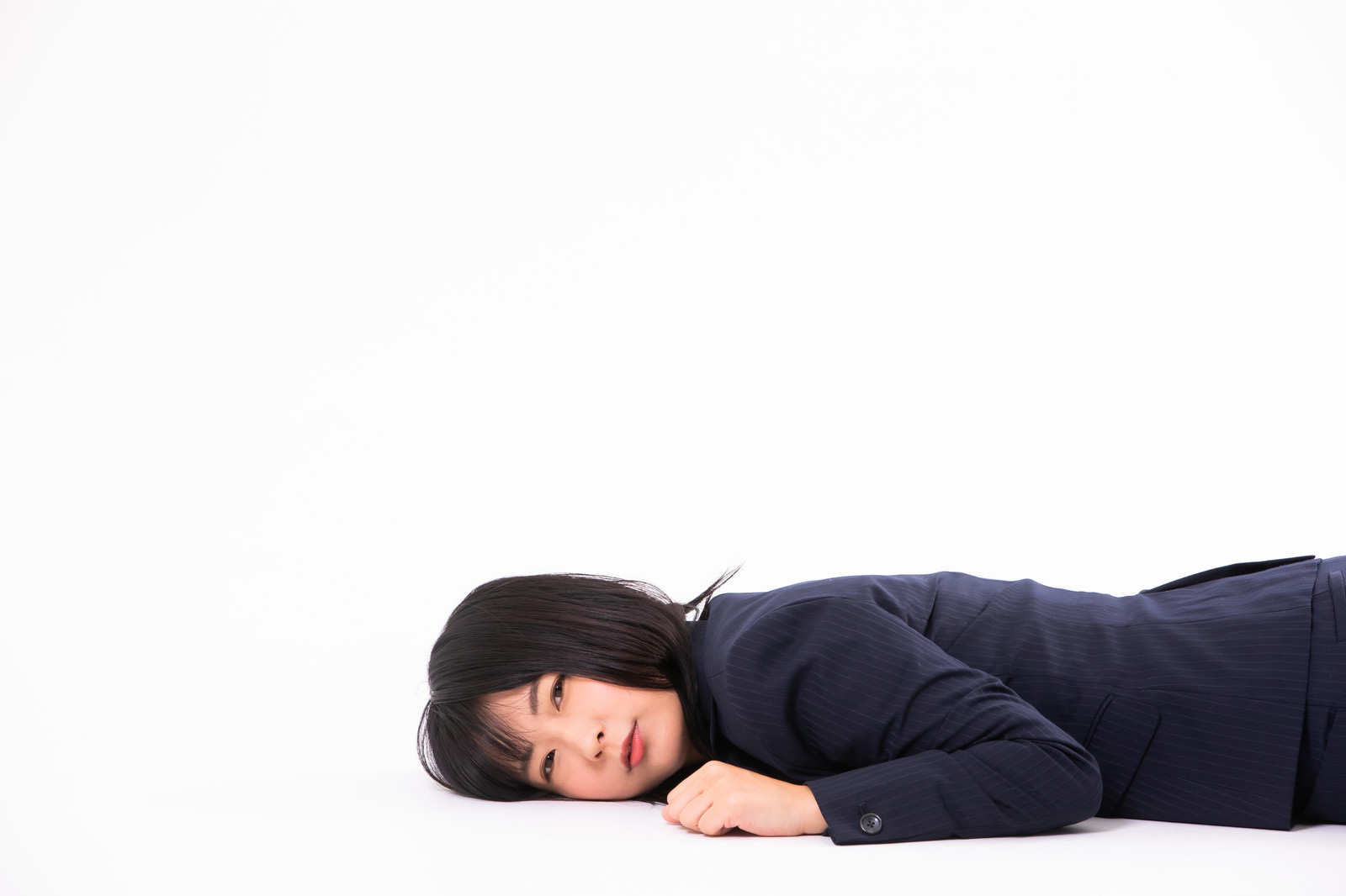 床に横たわって疲れ果てたスーツ姿の女性